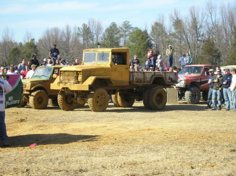 1993 Ford Bronco - A crowd gathers to watch a yellow military truck and other vehicles at an outdoor event.