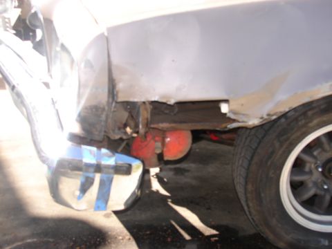 1973 Ford Ranchero - Low front-corner view of a white/primer car with the front fender bottom and inner structure cut away, exposing rust-perforated metal, a re…