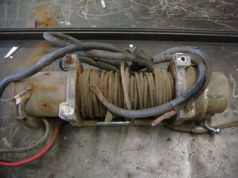 1996 Ford Bronco - A close-up view of a winch with its cable wound around the drum and electrical wiring attached.