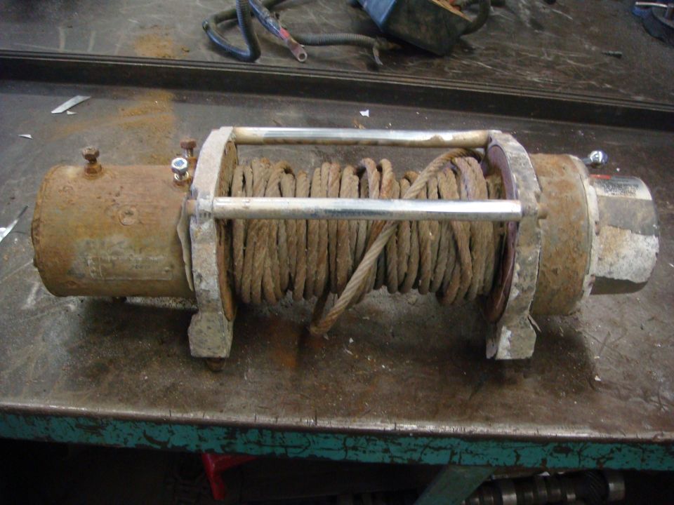 Rusty winch with coiled rope on a workbench