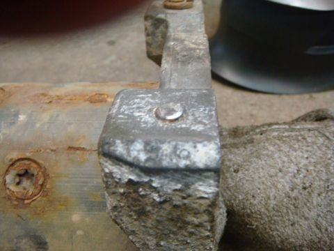1996 Ford Bronco - A close-up view of a heavily rusted metal bracket, showing a bolt and some corrosion.