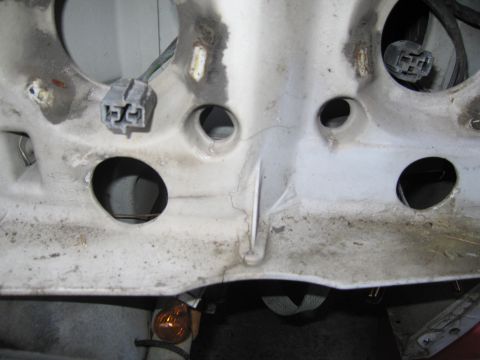 1991 Ford LTD Crown Victoria - This is a close-up view of a vehicle's headlight mounting bracket, showing its internal structure and wiring connectors.