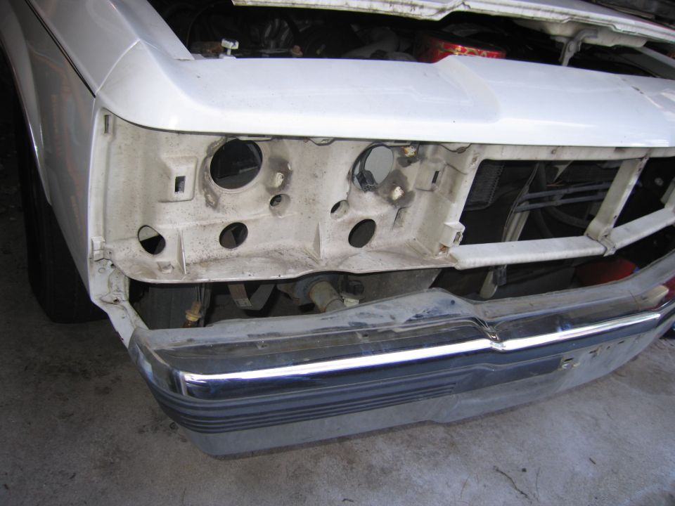 White 1991 Ford Crown Victoria LTD front end with missing headlights and grille, showing engine components