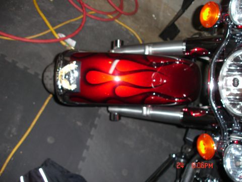 2006 Harley-Davidson FLHX - A close-up view of a motorcycle's fuel tank, a custom flame paint job and chrome accents.