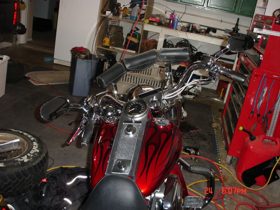 Red motorcycle with flame-painted tank and chrome bars in a garage
