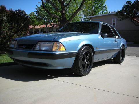 1990 Ford Mustang - Light blue 1990 Ford Mustang coupe with black aftermarket wheels.