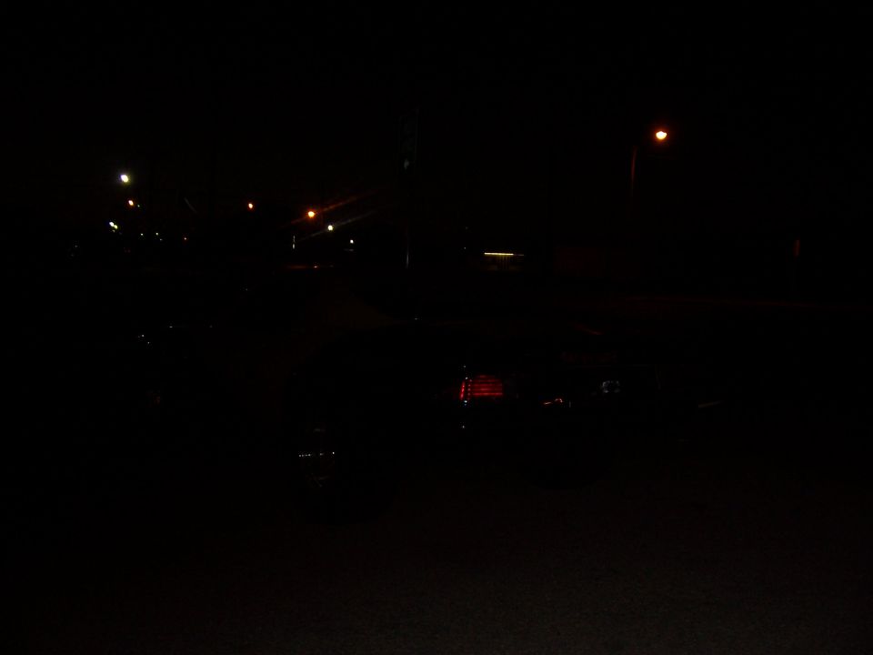 dark street scene at night with streetlights and reflections on wet pavement