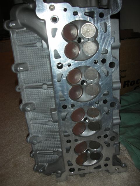 1998 Ford Crown Victoria - aluminum V8 cylinder head standing on edge, showing four three-valve combustion chambers with intake and exhaust valves.