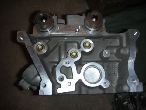 1998 Ford Crown Victoria - aluminum cylinder head rests deck-face-up on a dark carpet, showing machined ports and bolt holes.