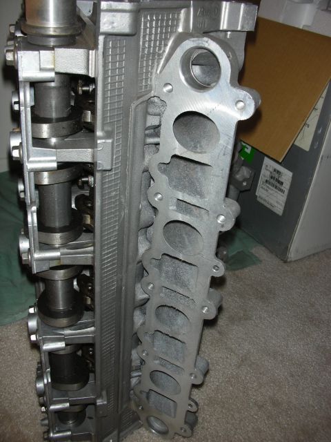 1998 Ford Crown Victoria - Side view of an aluminum cylinder head with visible camshaft, valvetrain, and a row of exhaust ports.