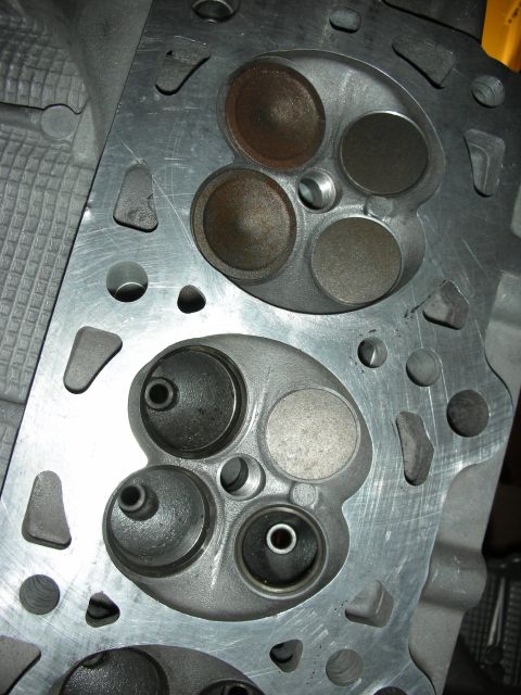 1998 Ford Crown Victoria - Macro shot of two combustion chambers on a cylinder head, each with intake and exhaust valve seats.