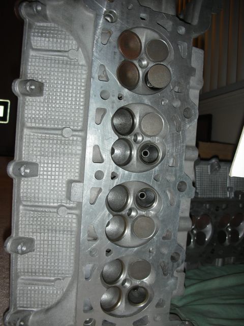 1998 Ford Crown Victoria - cylinder head's chamber face is shown with valve seats while a second head sits blurred behind it.