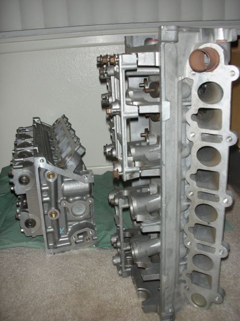 1998 Ford Crown Victoria - pair of aluminum cylinder heads rest on a green cloth, one upright showing ports, one lying flat.