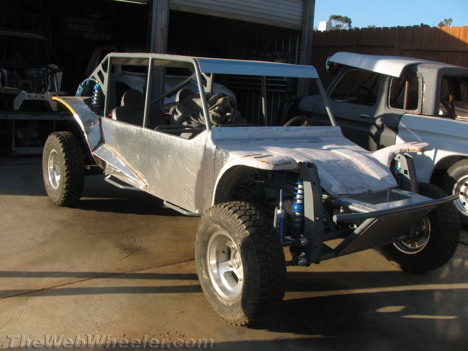 Bare-metal tube-chassis off-road buggy under construction in a shop yard