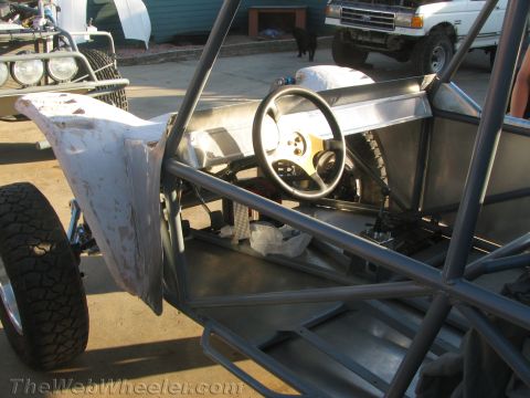 1990 Ford Bronco - Close-up of an off-road race vehicle's tube-frame interior showing the steering wheel, dash panel, and welded roll cage.