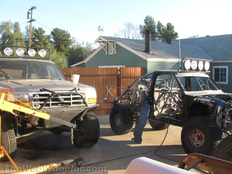 Lifted Ford truck and a tube-chassis race vehicle parked in a residential yard