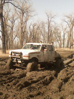 1992 Ford F-350 - This 1992 Ford F-350 is deep in the mud, with trees surrounding the off-road scene.