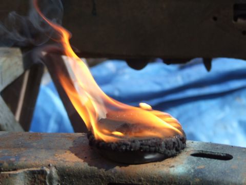 1967 Ford Bronco - A close-up view of a flaming object resting on a metal frame, with a blue tarp visible behind it.
