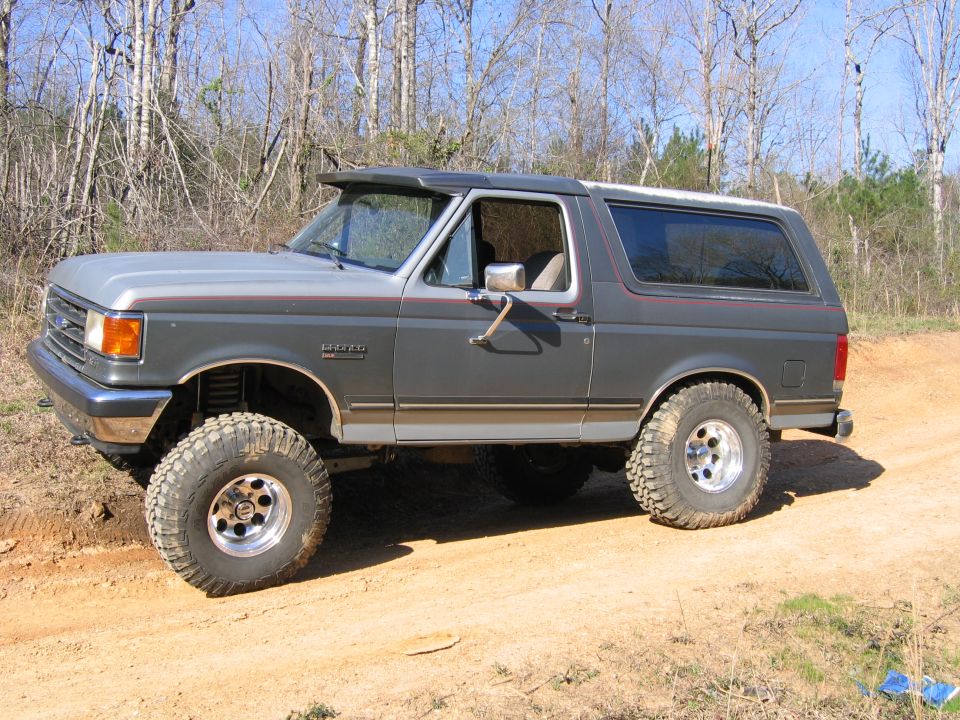 Gray Ford Bronco with lifted suspension and large tires on a dirt road