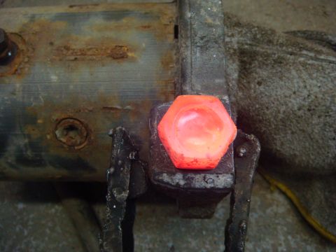 1996 Ford Bronco - Bolt head glowing red in a vise, indicating it is being heated for removal.