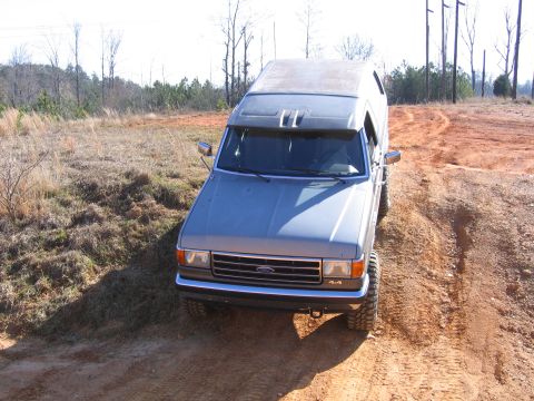 1989 Ford Bronco - This Ford Bronco is navigating a dirt trail with some off-road modifications.