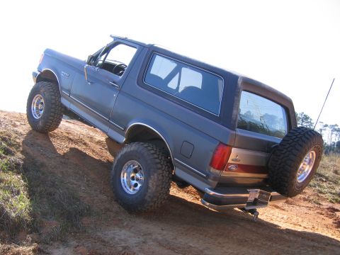 1989 Ford Bronco - This 1989 Ford Bronco is shown off-roading on a dirt incline, with its spare tire mounted on the rear.