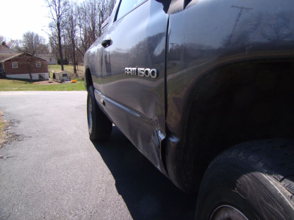 Side view of dark gray Dodge Ram 1500 with dented rear quarter panel