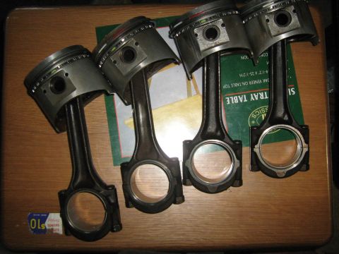 1981 Dodge Power Ram - Set of four pistons and connecting rods, likely for an engine rebuild. No vehicle is visible.