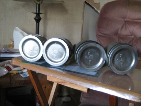1981 Dodge Power Ram - Four engine pistons are laid out on a table, with visible markings on their bases.