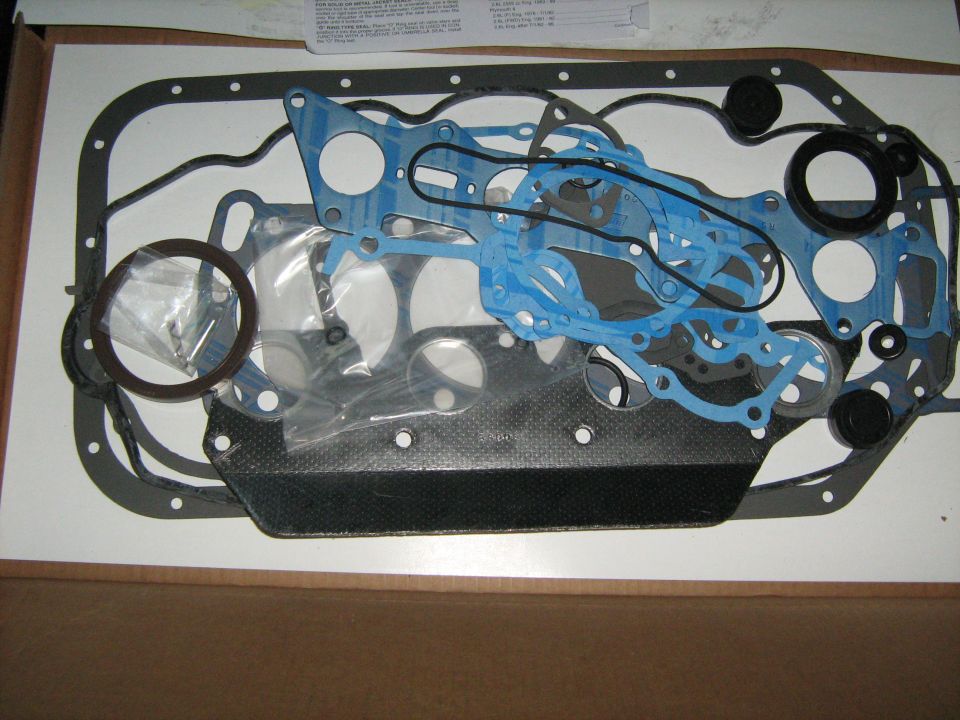 Engine overhaul gasket set laid out with black pan gasket, blue gaskets and seals