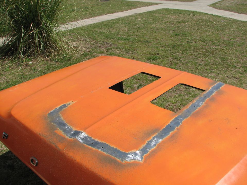 Orange hood with rectangular scoop openings cut in and bare metal mounting perimeter