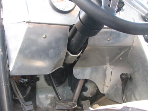 1990 Ford Bronco - Stripped vehicle interior showing the steering column, brake and gas pedals and unfinished aluminum dash panels.
