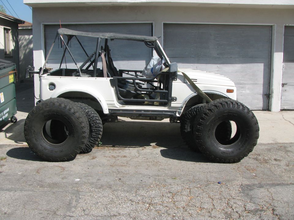 White 1987 Suzuki Samurai with oversized off-road tires and a soft top