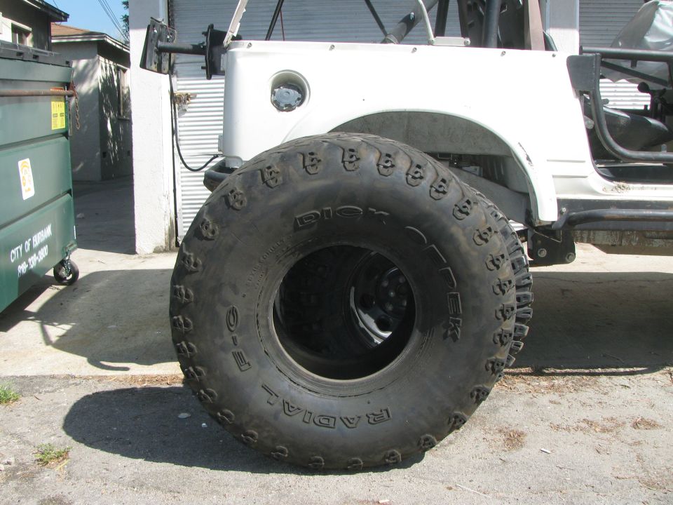 Oversized tire on white off-road vehicle, "DIX" visible on sidewall