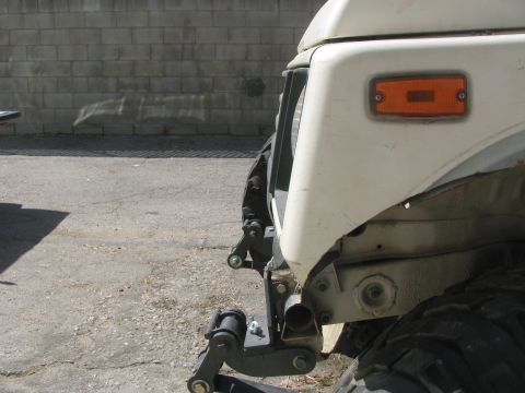 1987 Suzuki Samurai - Close-up view of the front fender, grille, and tire of a white Suzuki Samurai.