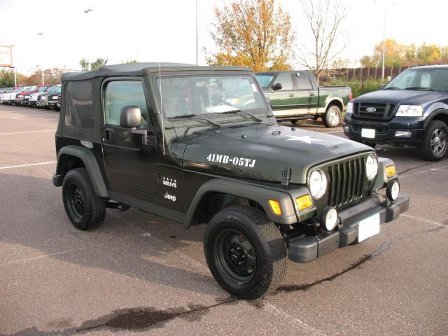 Dark green Jeep Wrangler with a soft top, black wheels, and a white star decal on the hood