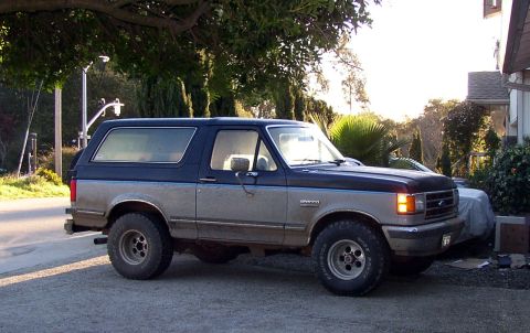 1989 Ford Bronco - Side view of a two-tone 1989 Ford Bronco parked outdoors.