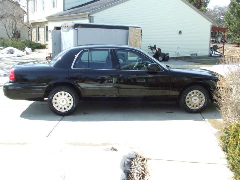 2003 Ford Crown Victoria - Side profile of a black 2003 Ford Crown Victoria sedan parked in a driveway.
