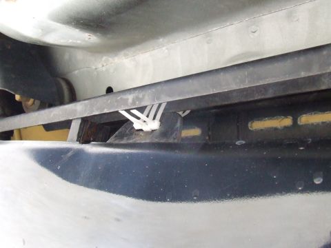 2003 Ford Crown Victoria - Close-up view of the undercarriage of a vehicle, showing a black bumper and a black bar secured with zip ties.