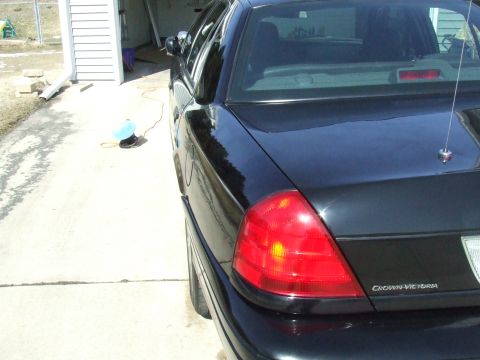 2003 Ford Crown Victoria - The rear of a black Ford Crown Victoria is shown, with the 'Crown Victoria' badge visible on the trunk lid.