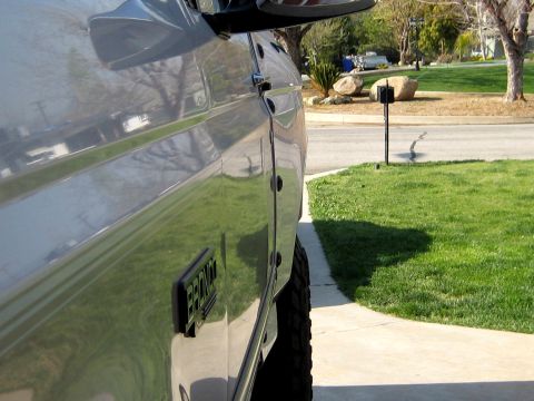 1996 Ford Bronco - Close-up side view of a gray Ford Bronco showing the driver-side body, door, and fender flare with a black 'BRONCO' emblem, parked on a con…