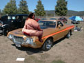 1971 Ford Ranchero - A man sits on the hood of a gold 1971 Ford Ranchero with an orange stripe. Another vehicle is visible in the background.