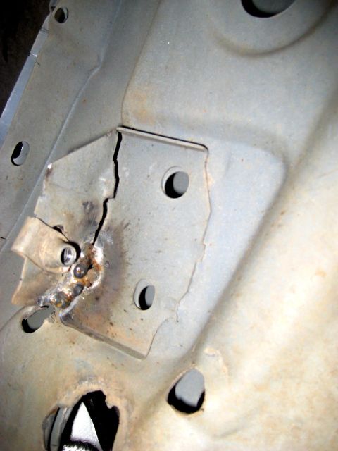 1996 Ford Bronco - Close-up of a gray sheet-metal inner body panel with a stamped bracket that has cracked around its weld, the fracture line running past a w…