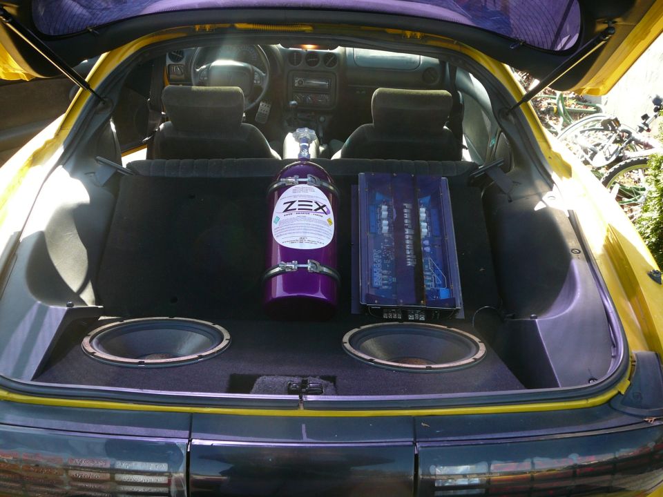 Purple ZEX nitrous bottle and Power Acoustik amp over dual subwoofers in yellow coupe hatch