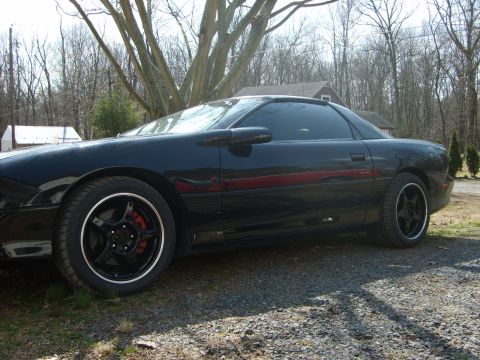 2002 Chevrolet Camaro - Side view of a black 2002 Chevrolet Camaro parked outdoors on a gravel surface.