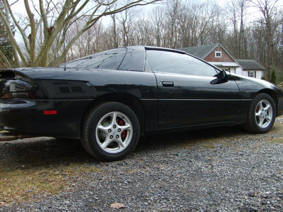 Black coupe with tinted windows, silver five-spoke wheels, and red brake calipers, viewed from the rear three-quarter angle