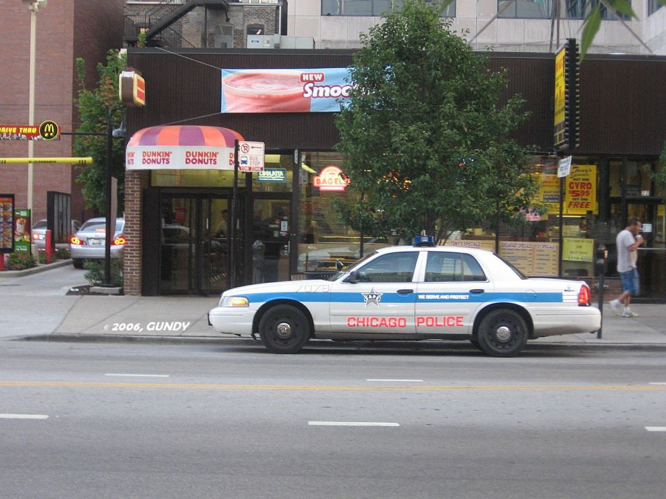 1999 Ford Crown Victoria police car, side view, parked in front of Dunkin' Donuts