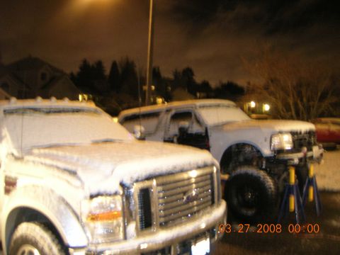 1996 Ford Bronco - A white SUV is parked on jack stands in the snow at night.