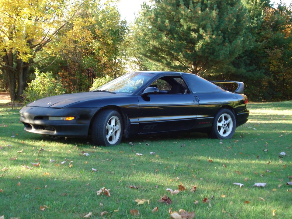 Black Ford Probe GT coupe parked on grass with autumn trees