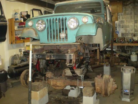 2005 Ford Excursion - A teal Jeep body is shown elevated on blocks with its frame and suspension components disassembled.